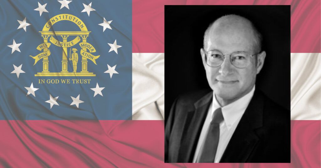 Martin Cowen appears in front of the Georgia flag in a headshot for his candidacy for Georgia Attorney General