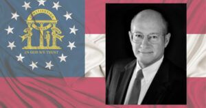 Martin Cowen appears in front of the Georgia flag in a headshot for his candidacy for Georgia Attorney General